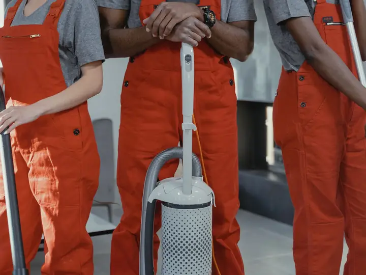 Members of a cleaning team in uniform with a vacuum cleaner