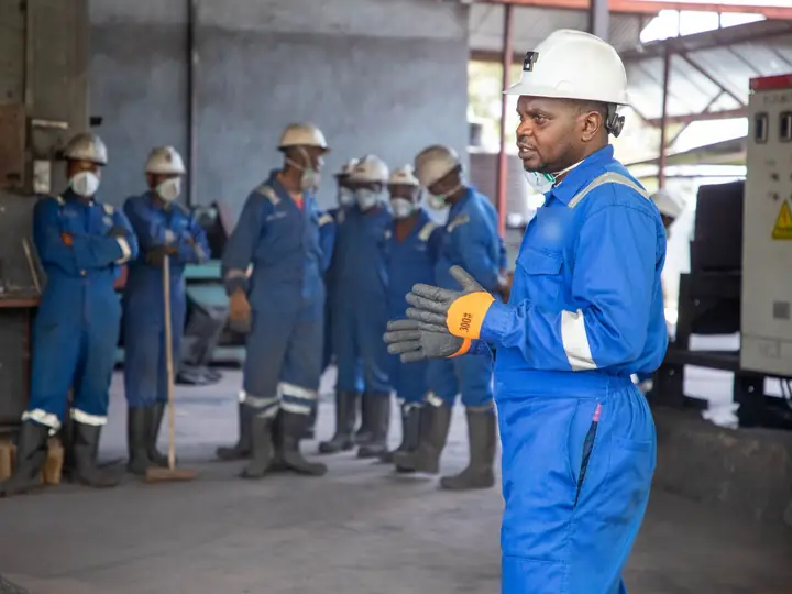 A trainer briefing a group of workers in overalls on site